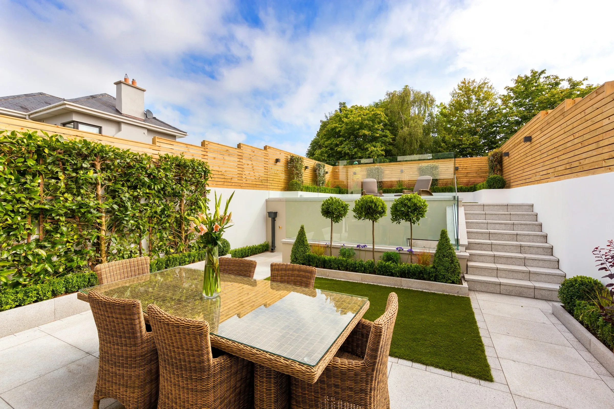 Terraced back garden with a porcelain patio, wide steps and clipped hedging